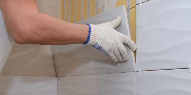 person putting tiling on the wall